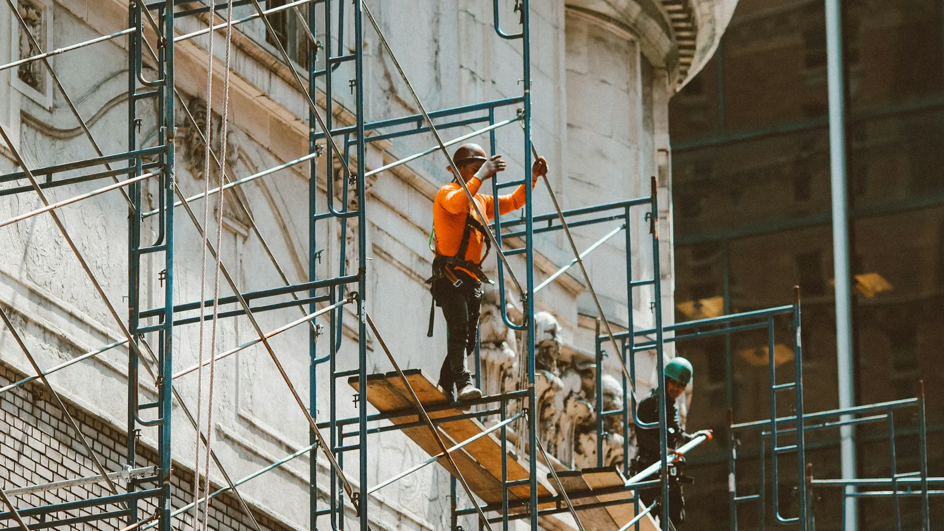 Operario sobre andamio trabajando en fachada de piedra histórica